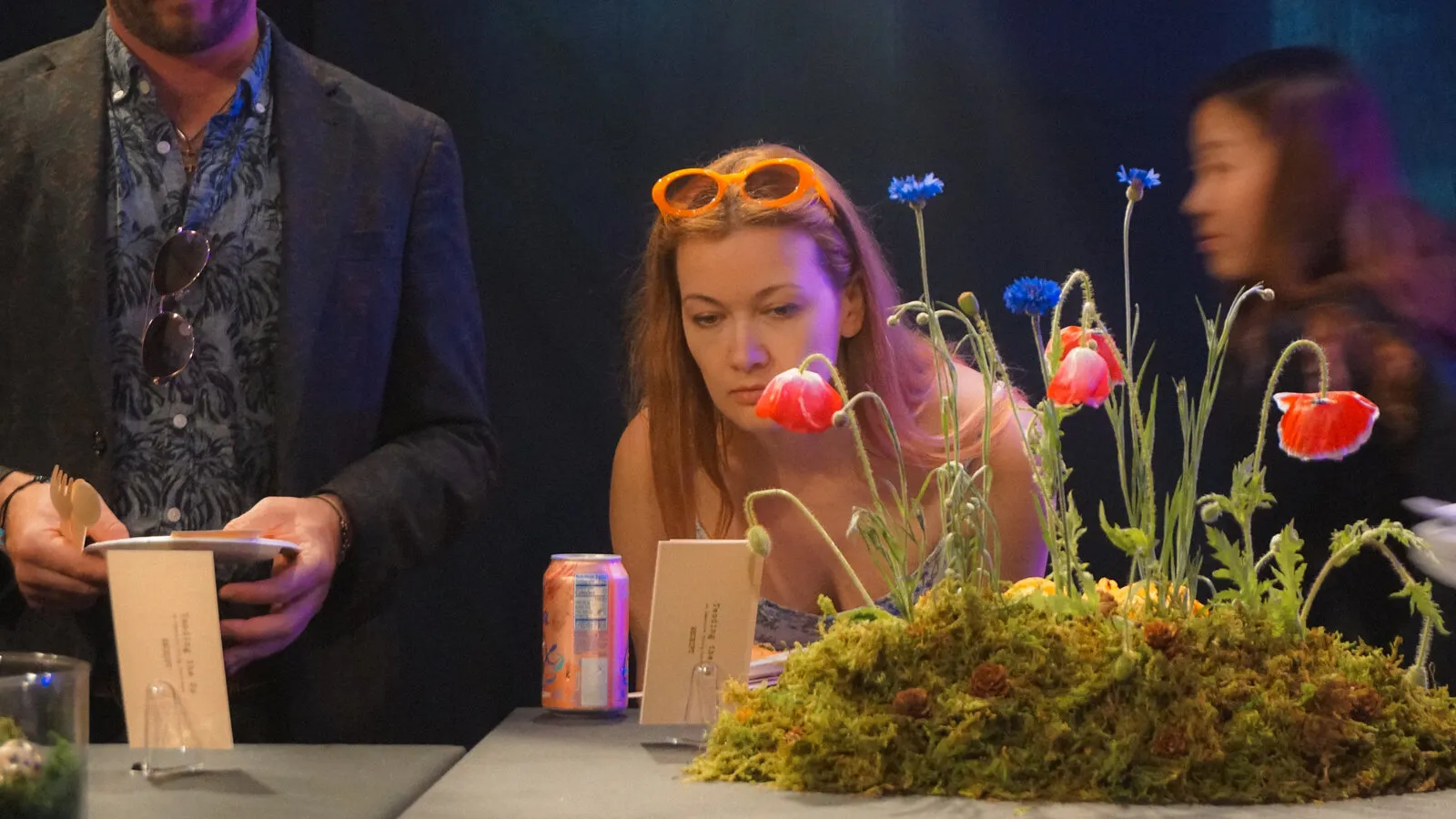 A guest leans in to smell wild poppies growing from the moss centerpiece
