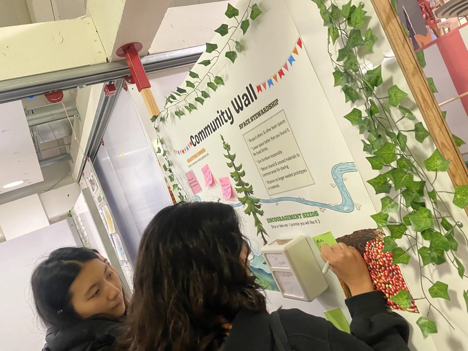 Two students placing an encouragement seed at the Community Wall during the Uganda pilot